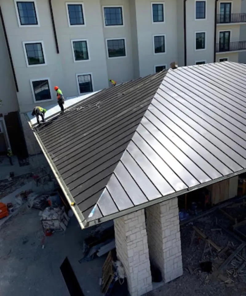 Crew installing standing seam metal roof panels on a commercial project in Pickerington